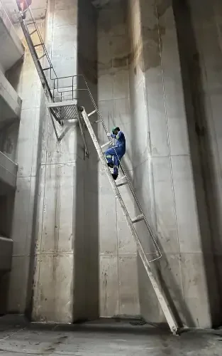 A worker climbing a steep staircase at a ship yard